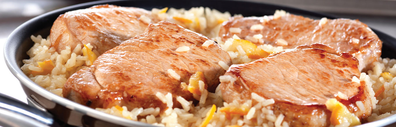 An image of prepared Quick Glazed Pork & Rice Skillet made with pork chops, onion, rice, Swanson® Chicken Broth, apricot preserves and Dijon-style mustard.