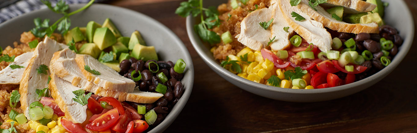 An image of prepared Quinoa Bowls with Avocado & Black Beans made with Swanson® Chicken Broth, Pace® Picante Sauce, quinoa, corn, black beans, avocado, tomatoes, green onion, chicken and cilantro.