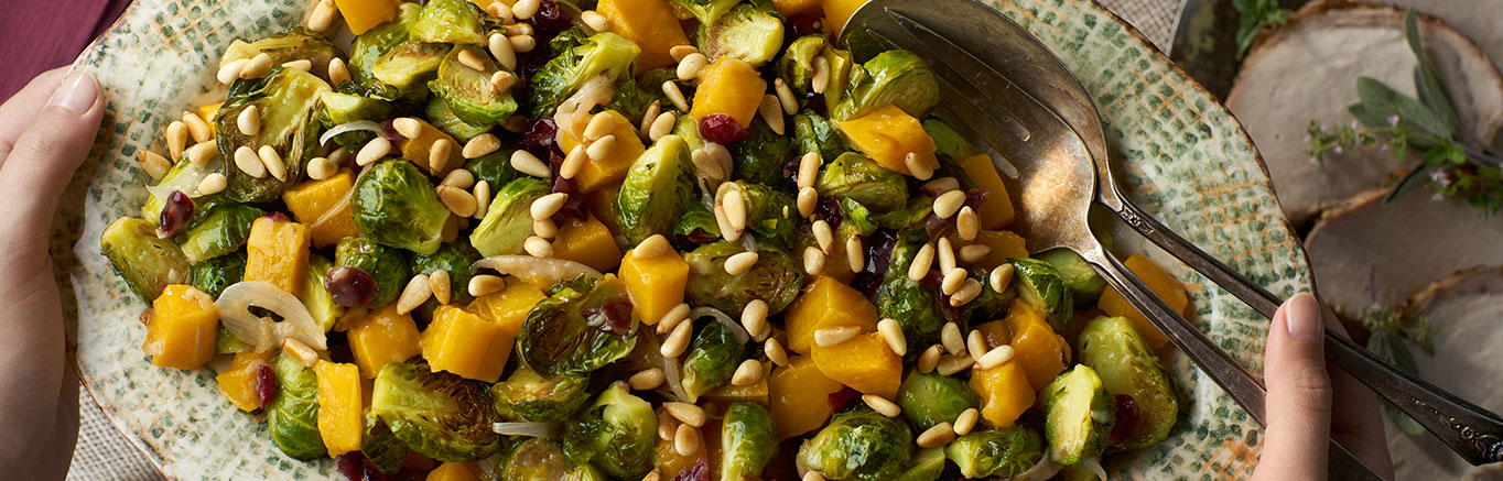 An image of prepared Roasted Brussels Sprouts & Squash with Cranberries & Pine Nuts made with Brussels sprouts, butternut squash, white wine, Swanson® Chicken Broth, cranberries and pine nuts.