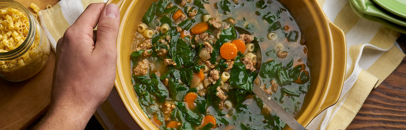 An image of prepared Sausage & Spinach Soup made with sweet Italian pork sausage, onion, carrot, Swanson® Chicken Broth, spinach, ditalini pasta and Parmesan cheese.