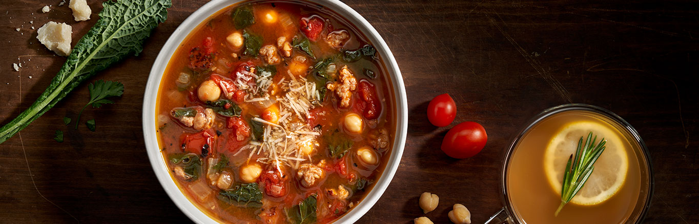 An image of prepared Sausage Kale Soup made with pork sausage, onion, fired roasted tomatoes, kale, chickpeas, Swanson® Chicken Bone Broth, Parmesan cheese and parsley.