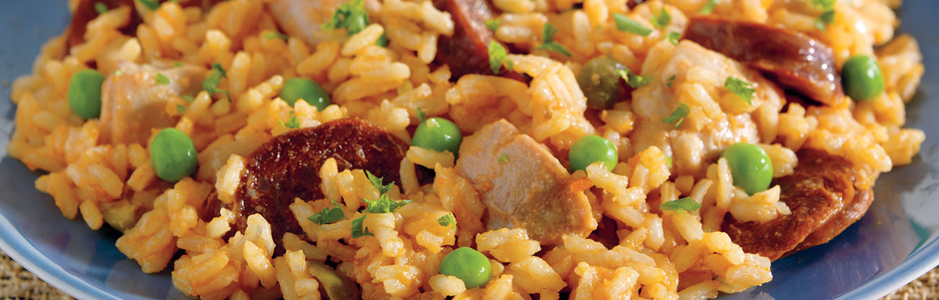 An image of prepared Slow-Cooked Chicken & Sausage Paella made with chicken, chorizo sausage, onion, Swanson® Chicken Broth, Campbell's® Condensed Tomato Soup, instant white rice, peas, green olives and parsley.