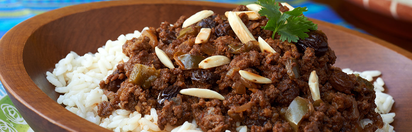 An image of prepared Slow-Cooked Picadillo made with ground beef, onion, Swanson® Beef Broth, Pace® Picante Sauce, raisins, almonds and white rice.