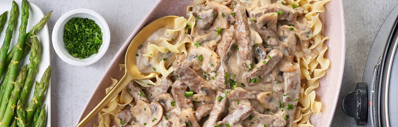 An image of prepared Slow Cooker Creamy Beef Stroganoff made with Campbell's® Condensed Cream of Mushroom Soup, Swanson® Beef Broth, mushrooms, onion, beef round steak, egg noodles and sour cream.