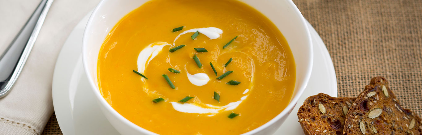 An image of prepared Slow Cooker Vegetable & Butternut Squash Soup made with Gala apples, butternut squash, carrots, onion, garlic, sage, Swanson® Vegetable Broth, half and half and sour cream.