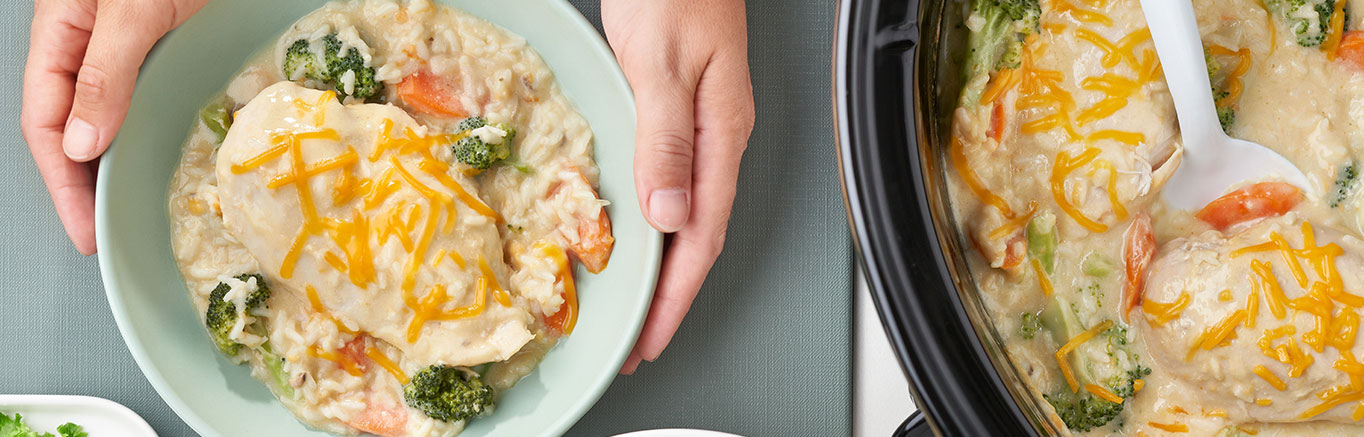 An image of prepared Slow Cooker Chicken, Broccoli & Rice made with Cheddar cheese, Campbell's® Condensed Cream of Chicken and Mushroom Soup, Campbell's® Condensed Cream of Chicken Soup, Swanson® Chicken Broth, broccoli, carrots, chicken and instant white rice.