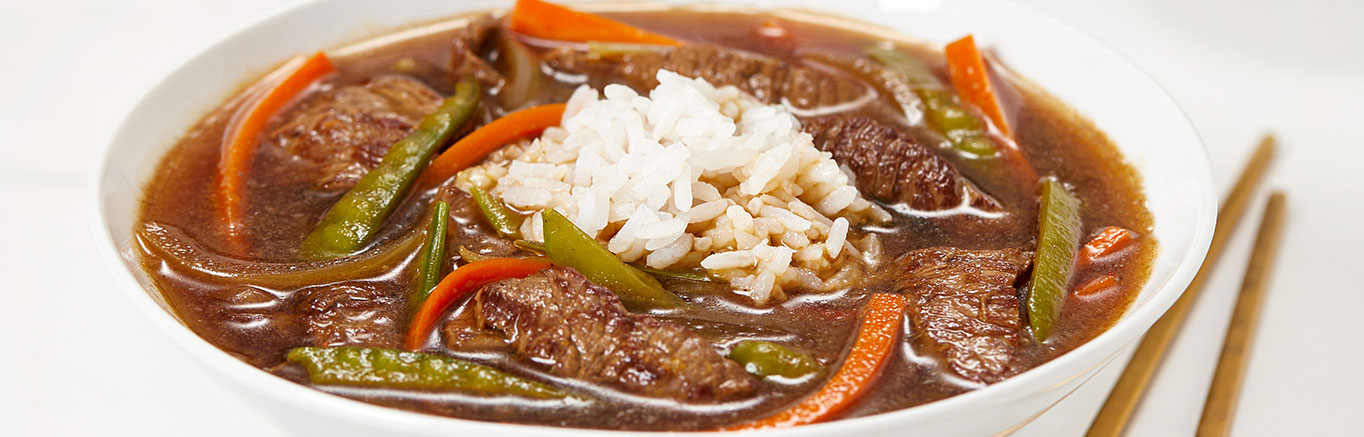 An image of prepared Spicy Asian Beef & Snow Pea Soup made with beef sirloin steak, carrot, snow peas, onion, Swanson® Beef Broth and jasmine rice.
