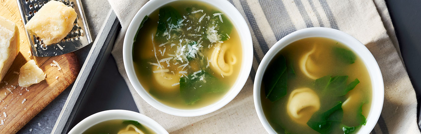 An image of prepared Spinach Tortellini Soup made with Swanson® Natural Goodness Chicken Broth, garlic powder, cheese tortellini and fresh spinach.