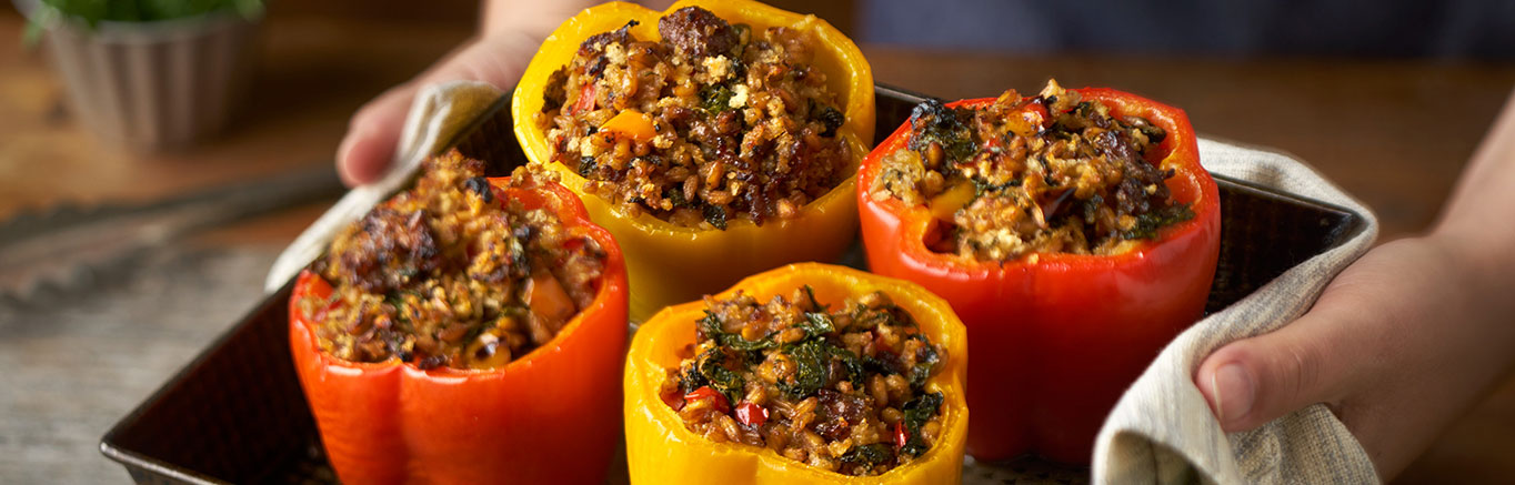 An image of prepared Stuffed Peppers with Kale & Farro made with onion, sweet Italian pork sausage, Swanson® Chicken Broth, farro, kale, panko and Parmesan cheese.