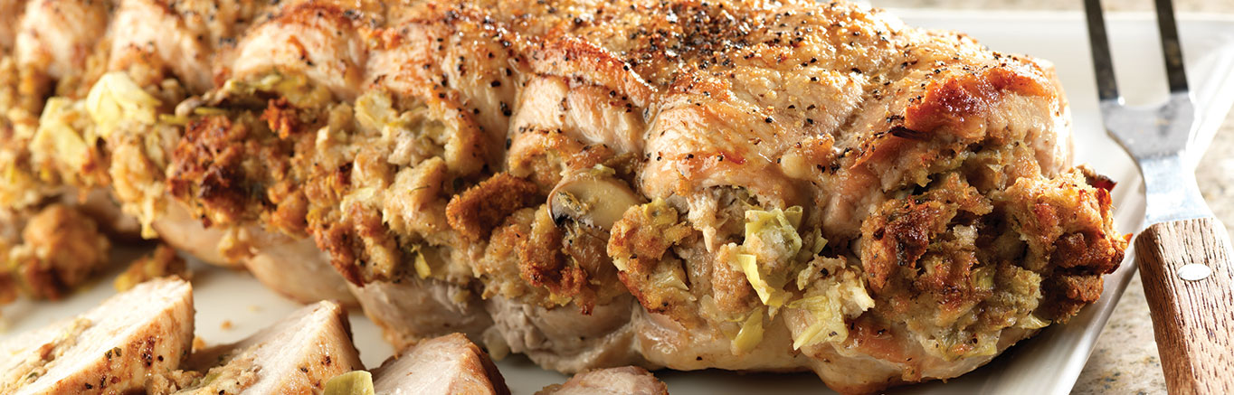An image of prepared Stuffed Pork Roast with Herb Seasoned Artichoke & Mushroom Stuffing made with green onion, Swanson® Chicken Broth, artichoke hearts, mushrooms, Pepperidge Farm® Herb Seasoned Stuffing and pork loin roast.
