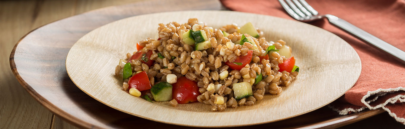 An image of prepared Summer Farro Salad made with Swanson® Vegetable Broth, farro, grape tomatoes, cucumber, corn, basil and Parmesan.