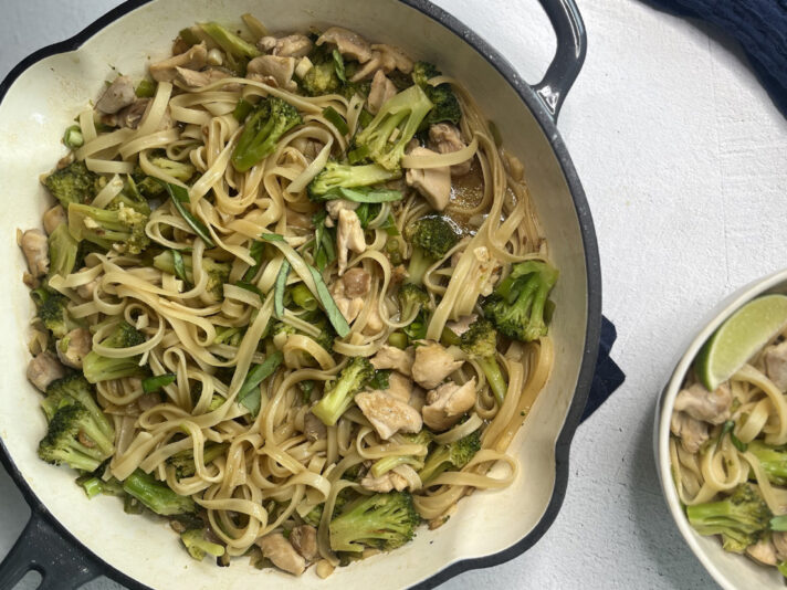 An image of prepared Chicken Drunken Noodles made with chicken thighs, garlic, Thai chili peppers, Swanson® Chicken Bone Broth, rice noodles, broccoli, lime, green onion and basil.