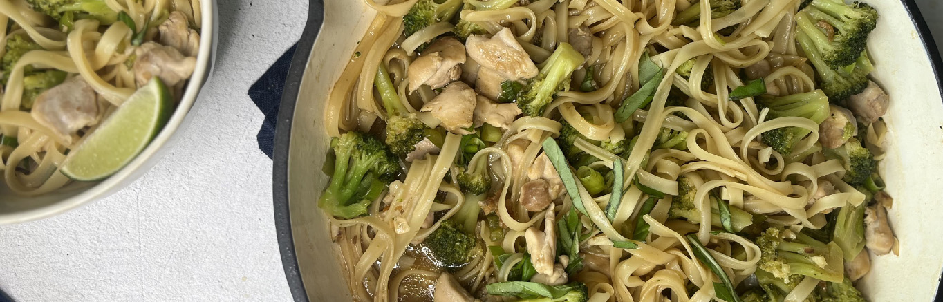 An image of prepared Chicken Drunken Noodles made with chicken thighs, garlic, Thai chili peppers, Swanson® Chicken Bone Broth, rice noodles, broccoli, lime, green onion and basil.