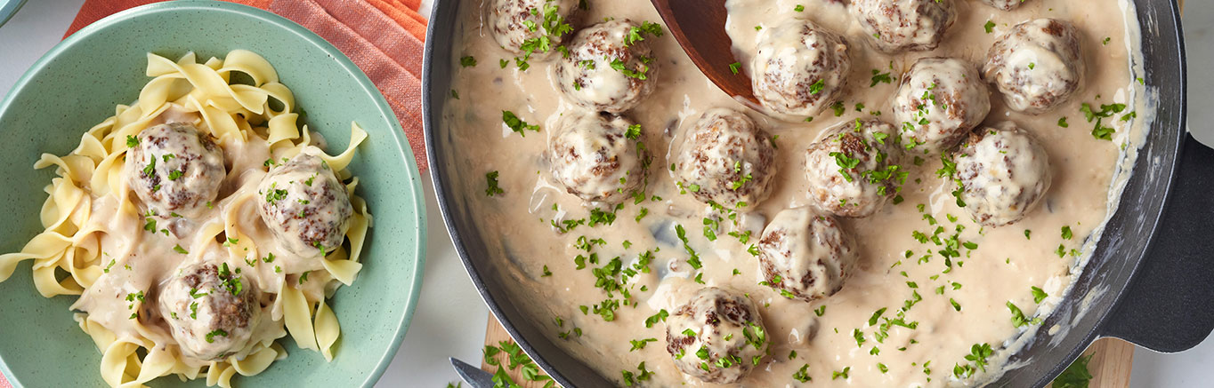 An image of prepared Swedish Meatballs made with ground turkey or ground beef, onion, Swanson® 50% Less Sodium Beef Broth, Campbell's® Condensed Cream of Mushroom Soup, sour cream and egg noodles.