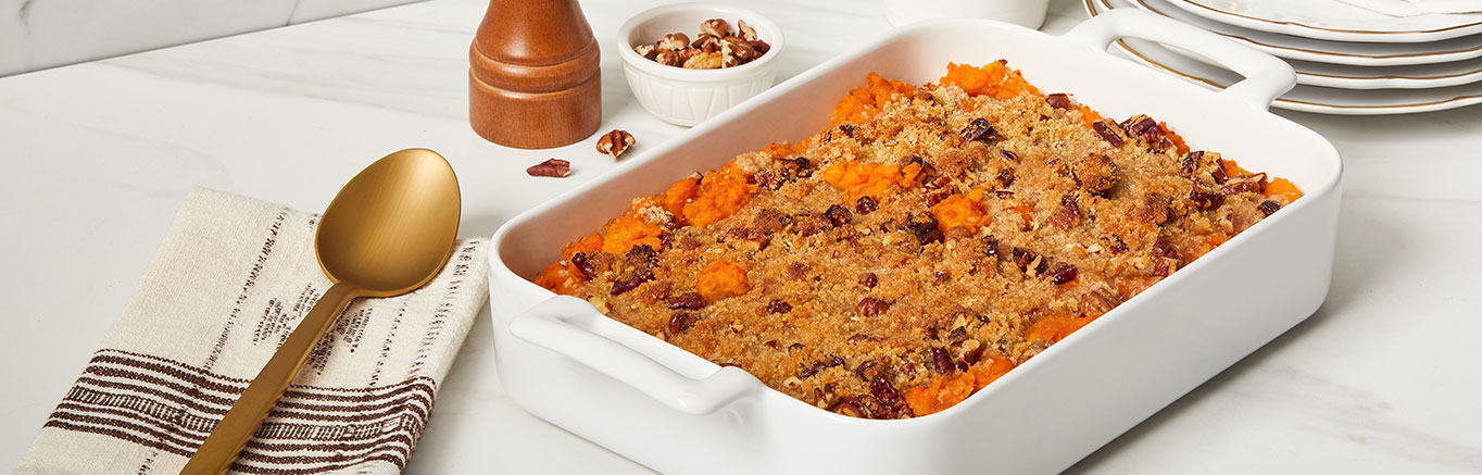 An image of prepared Sweet Potato Casserole made with butter, sweet potatoes, Swanson® Chicken Broth, brown sugar and pecans.