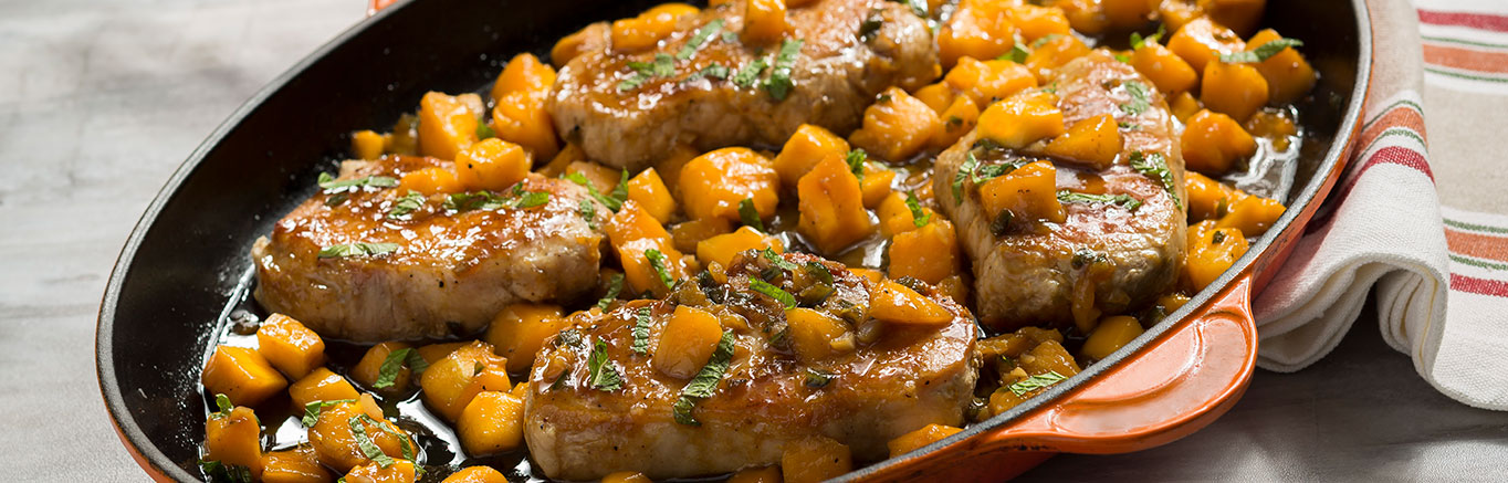 An image of prepared Sweet & Spicy Mango Glazed Pork Chops made with pork chops, Swanson® Natural Goodness® Chicken Broth, brown sugar, mango and mint.