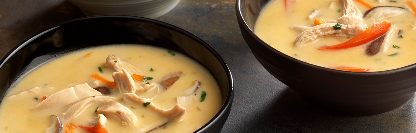 An image of prepared Thai Chicken and Vegetable Soup made with red bell pepper, mushrooms, Swanson® Chicken Broth, unsweetened coconut milk, chicken, lime and cilantro.
