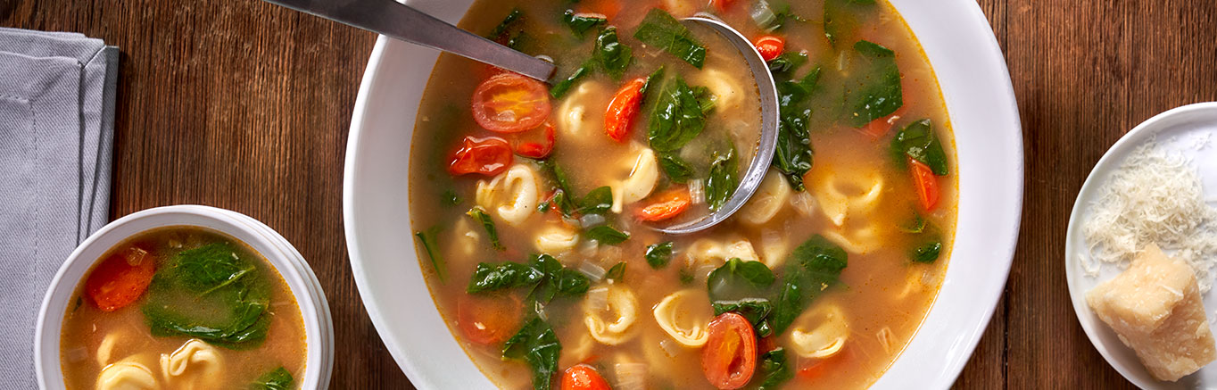 An image of prepared Tortellini en Brodo with Tomatoes & Spinach made with onion, grape tomatoes, garlic, Swanson® Natural Goodness® Chicken Broth, cheese tortellini, baby spinach and Parmesan cheese.