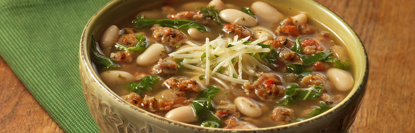 An image of prepared Tuscan White Bean Soup made with Italian-style chicken sausage, onion, white wine, Swanson® Natural Goodness® Chicken Broth, kale, cannellini beans, parsley and Parmesan cheese.
