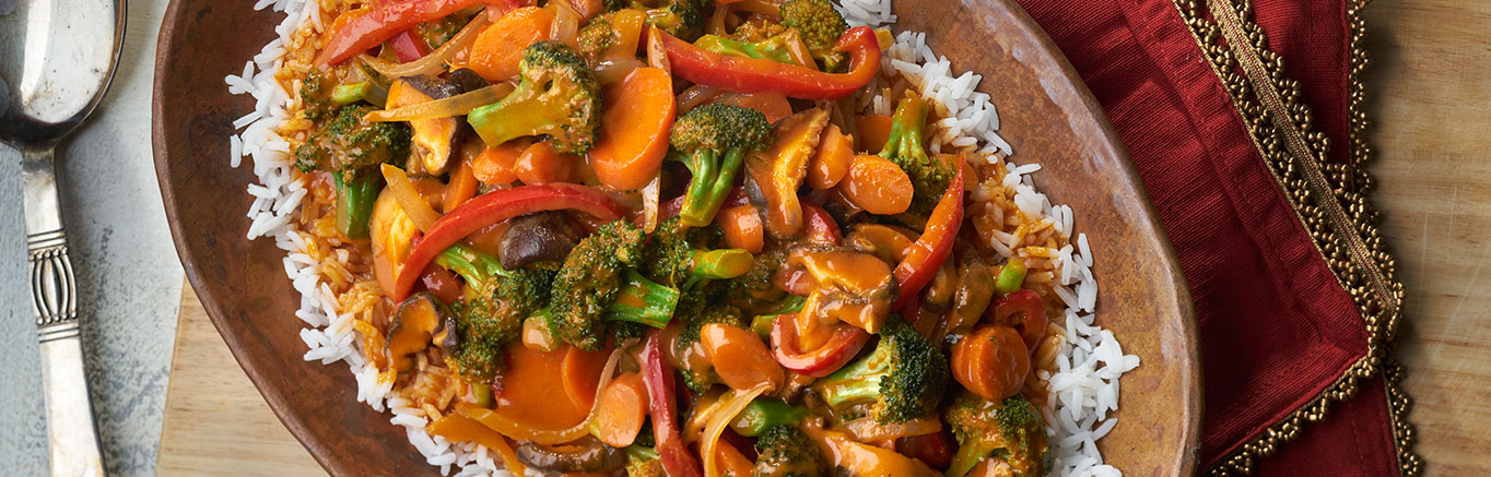 An image of prepared Vegetable Curry over Jasmine Rice made with onion, broccoli, red bell pepper, shiitake mushrooms, red curry paste, coconut milk, Swanson® Vegetable Broth and jasmine rice.