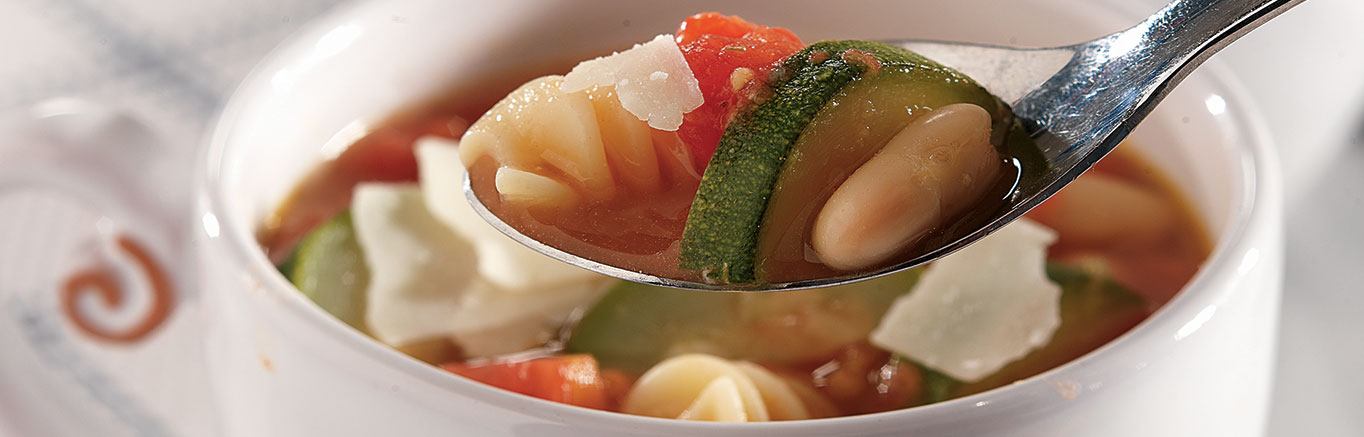 An image of prepared Vegetable Minestrone Soup made with carrot, green beans, zucchini, Swanson® Vegetable Broth, canned diced tomatoes, white cannellini beans, rotini pasta and Parmesan.
