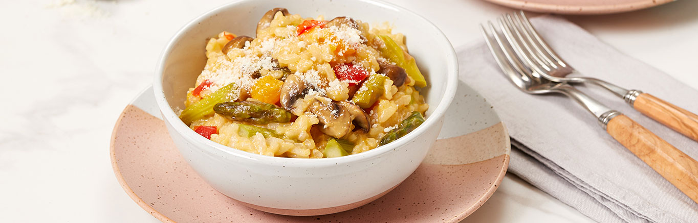 An image of prepared Vegetable Risotto made with red bell pepper, butternut squash, mushrooms, arborio rice, white wine, Swanson® Vegetable Stock, asparagus and Parmesan.