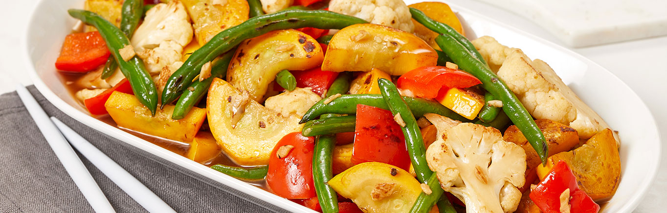 An image of prepared Garlic Sautéed Vegetables made with red bell pepper, cauliflower florets, green beans, yellow squash, garlic and Swanson® Chicken Broth.