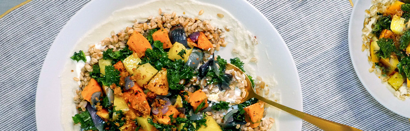 An image of prepared Baked Veggie Farro Salad with Creamy Whipped Feta made with farro, Swanson® Chicken Broth, butternut squash, red onion, kale and feta cheese.