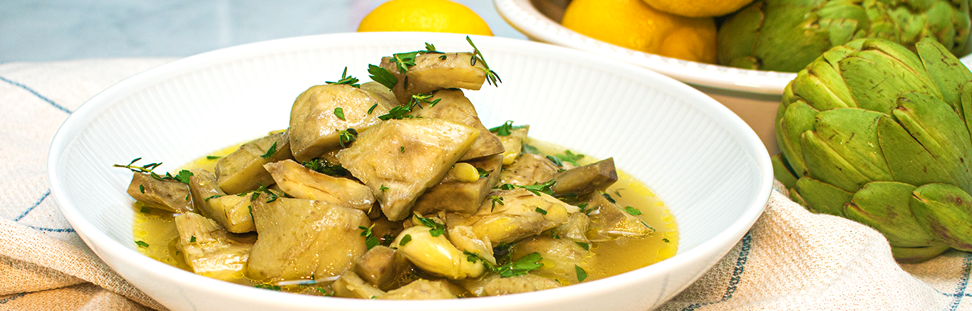 An image of prepared Braised Artichokes with White Wine and Herbs made with Swanson® Chicken Broth, white wine and artichokes.