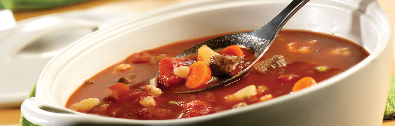 An image of prepared Savory Vegetable Beef Soup made with Swanson® Beef Broth, potatoes, beef, V8® 100% Vegetable Juice, tomatoes, frozen mixed vegetables and thyme.