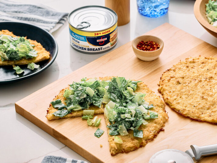 An image of prepared Viral Chicken Crust Caesar Salad Pizza made with Swanson® Premium White Chicken Breast in Water, mozzarella cheese, Parmesan cheese, eggs, romaine lettuce and Caesar dressing.