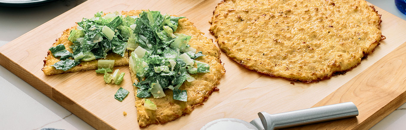An image of prepared Viral Chicken Crust Caesar Salad Pizza made with Swanson® Premium White Chicken Breast in Water, mozzarella cheese, Parmesan cheese, eggs, romaine lettuce and Caesar dressing.
