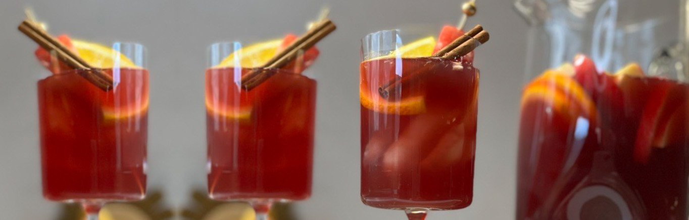 An image of prepared Autumn Sangria made with red wine, V8 Energy® Sparkling Orange Pineapple, apple cider, bourbon, apple, orange and cinnamon sticks.