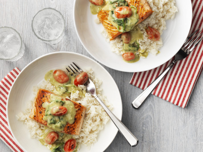 An image of prepared Salmon with Creamy Pesto Sauce made with salmon, grape tomatoes, Campbell's® Condensed Cream of Mushroom Soup, basil pesto, baby spinach and brown or white rice.