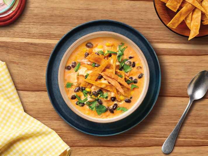 An image of prepared Slow Cooker Chicken Tortilla Soup made with chicken, Pace® Picante Sauce, Campbell's® Condensed Cream of Chicken Soup, corn, black beans, corn tortillas, Cheddar cheese and cilantro.