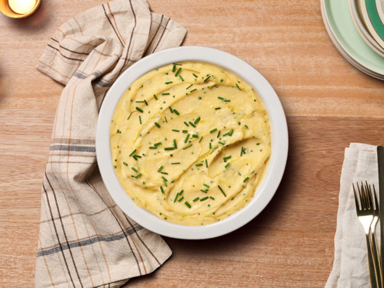 An image of prepared Cheddar Horseradish Mashed Potatoes showing russet potatoes, Swanson® Natural Goodness® Chicken Broth, Campbell's® Condensed Cheddar Cheese Soup, sour cream and horseradish mashed together and topped with fresh chives.