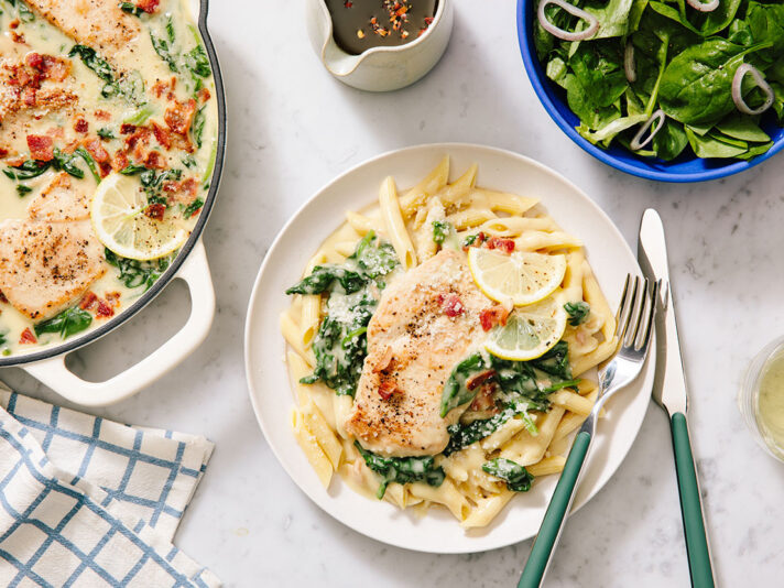 An image of prepared Creamy Garlic & Bacon Parmesan Chicken with Spinach showing chicken, bacon, baby spinach, Campbell's® Condensed Cream of Chicken Soup, Swanson® Unsalted Chicken Broth, Parmesan cheese and lemon juice.