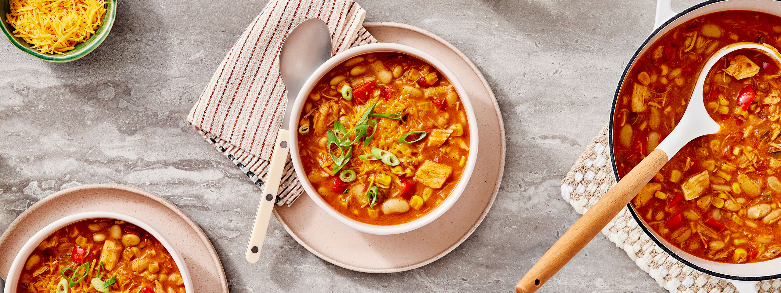 An image of prepared White Chicken Chili made with corn, bell pepper, chicken, Campbell's® Condensed Cream of Chicken Soup, Pace® Chunky Salsa, cannellini beans, Cheddar cheese and green onions.