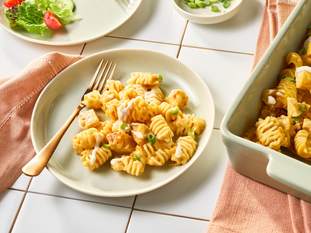 An image of prepared Creamy Buffalo Chicken Mac & Cheese made with radiatore pasta, Campbell's® Condensed Spicy Buffalo-Style Cream of Chicken Soup, chicken, Monterey Jack cheese and green onion.