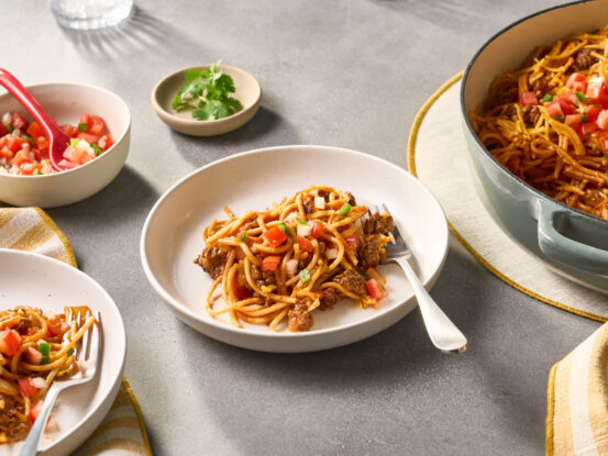 An image of prepared Quick One Pot Spicy Taco Spaghetti made with ground beef, onion, Swanson® Natural Goodness® Chicken Broth, Campbell's® Condensed Spicy Tomato Soup, spaghetti, Cheddar cheese and pico de gallo.